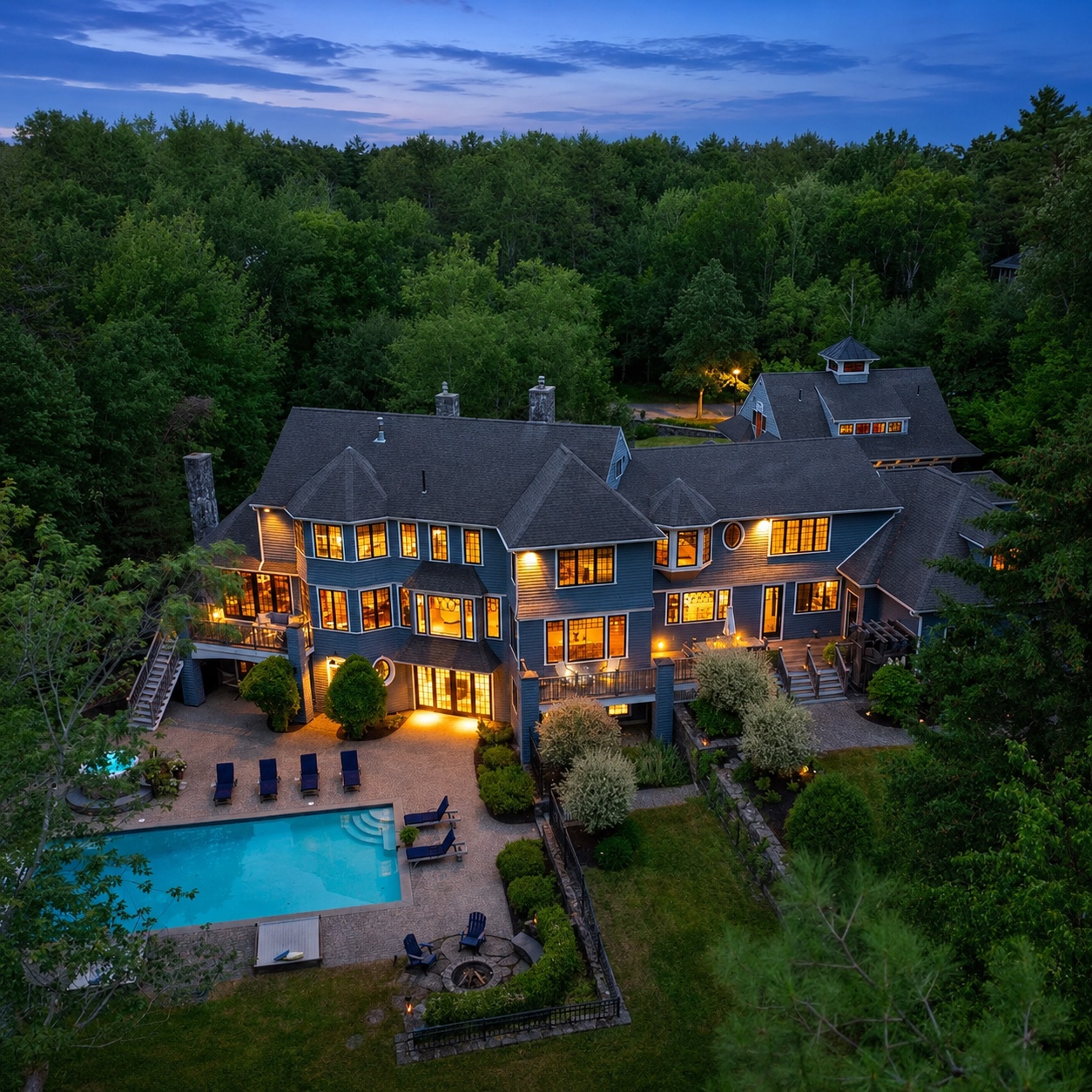 Russ Doucette home illuminated at dusk above the wooded Maine landscape