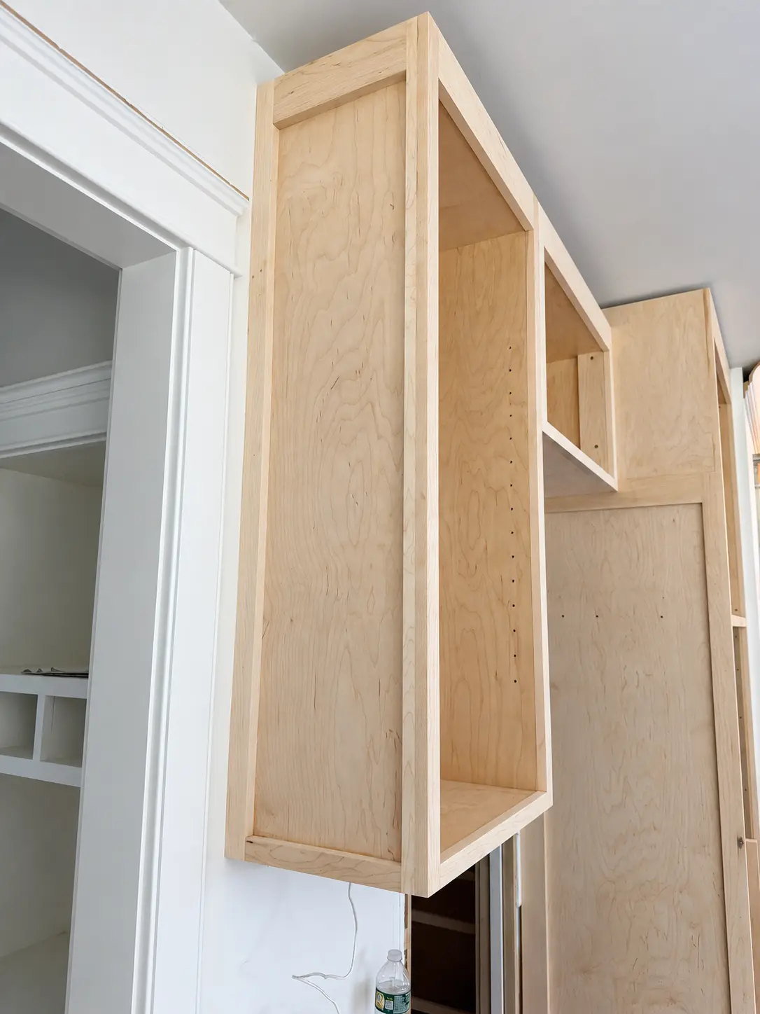 Unfinished cabinetry being fitted beside an interior doorway
