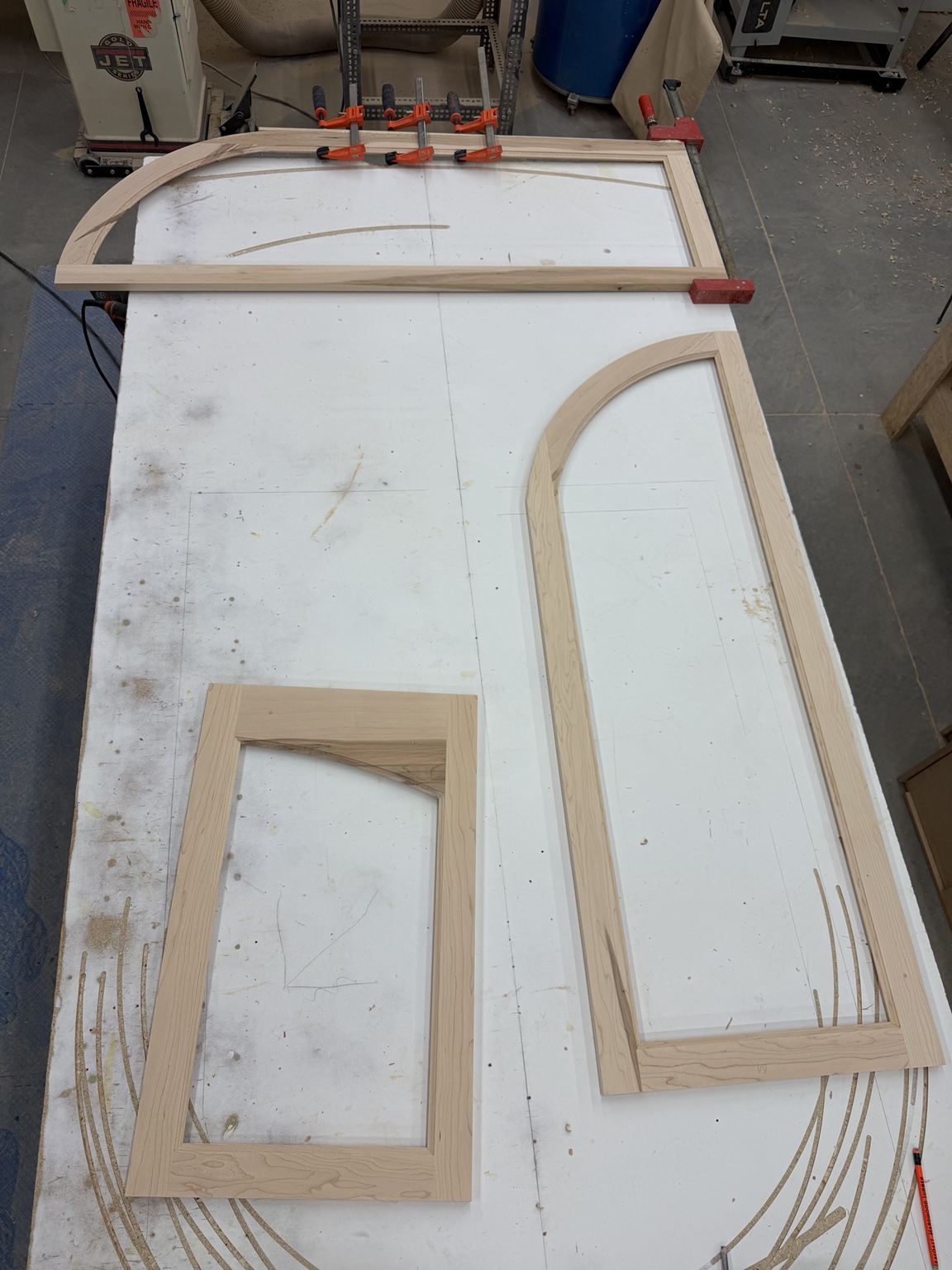 Three wood frames with different curved profiles arranged on a marked layout table