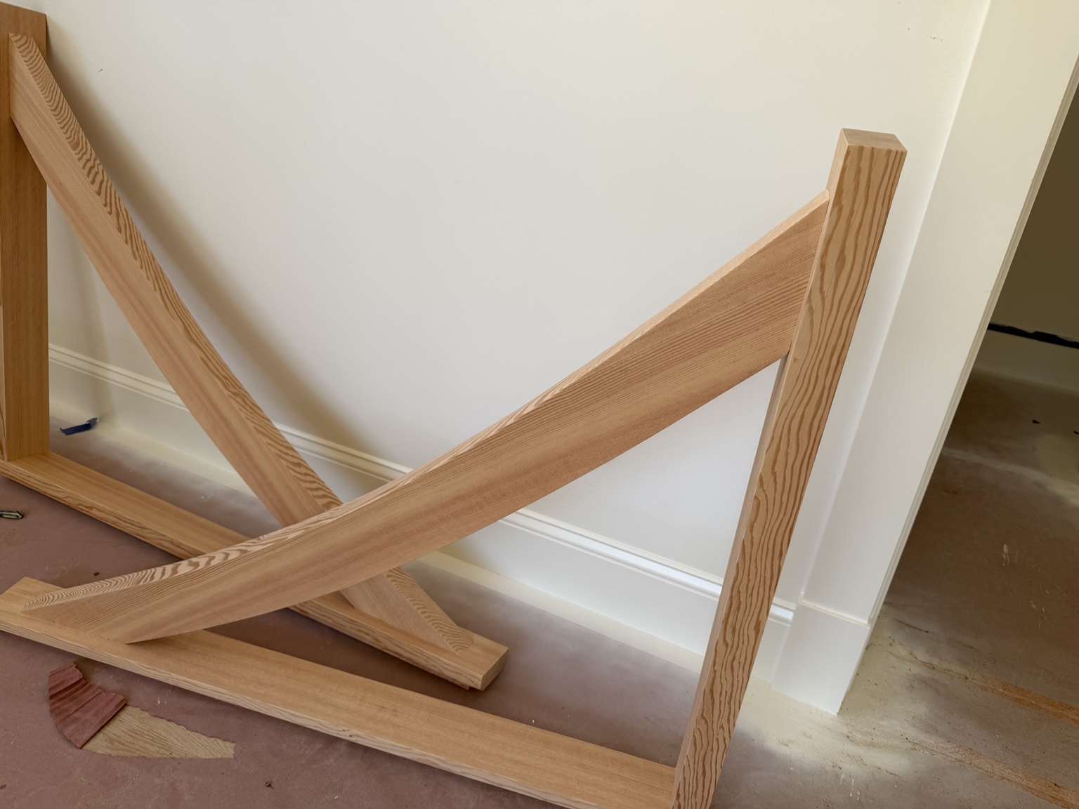 Curved wood components resting against a wall with their profiles and grain visible