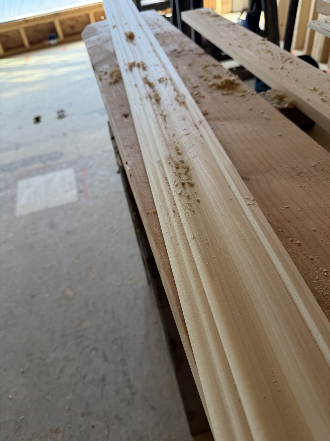 Long shaped wood profile on a workbench with wood shavings along its surface