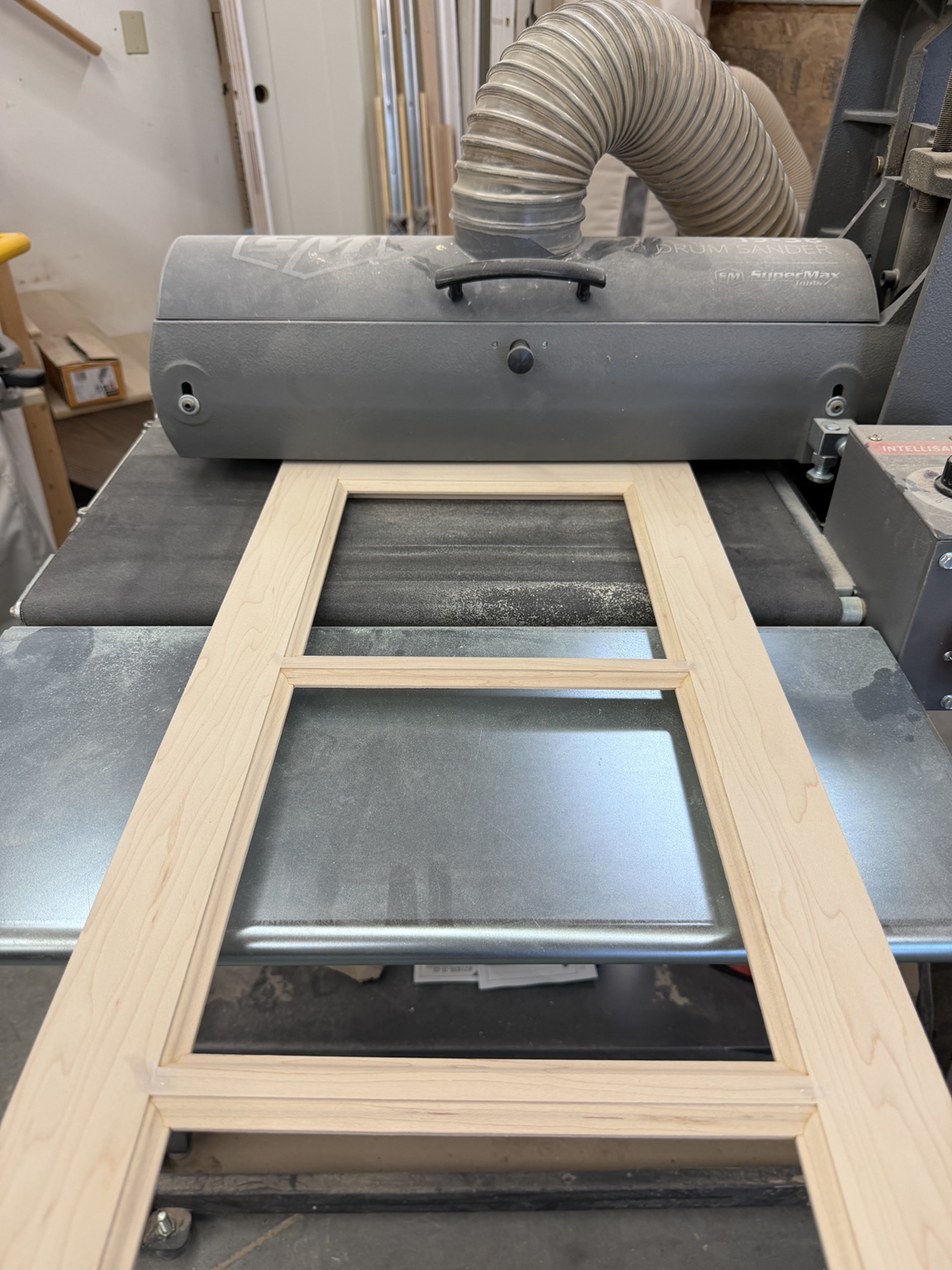 Rectangular wood frame positioned at a drum sander in the wood shop