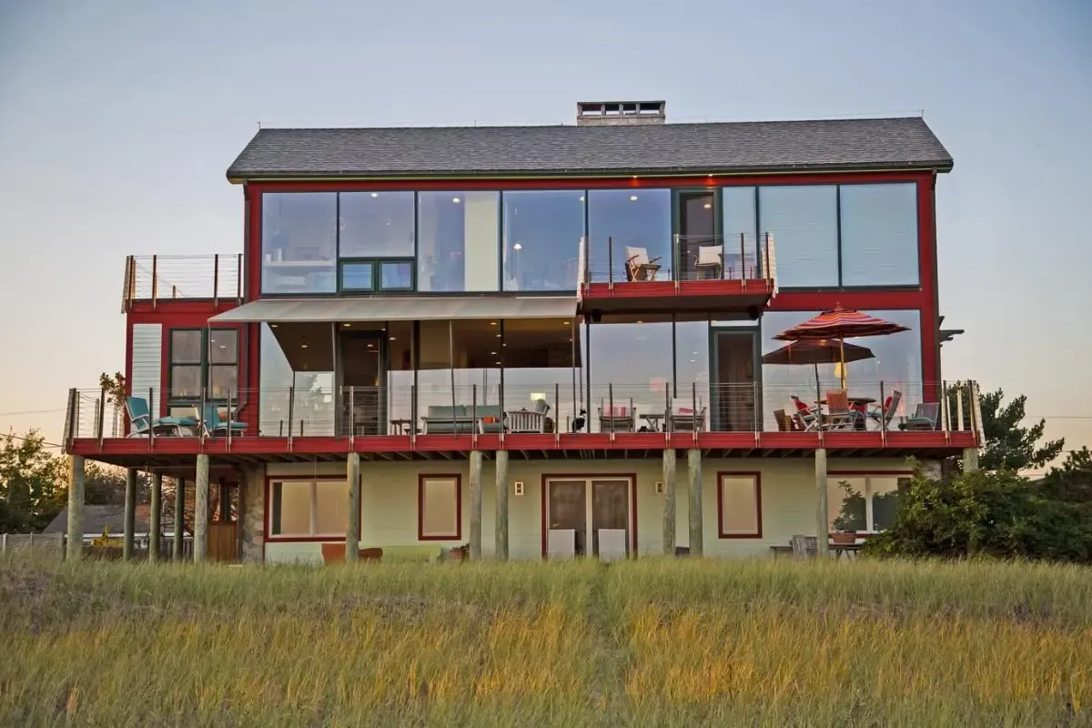 Pine Point Beach residence in Scarborough, Maine, with red-framed glass walls and a wide coastal deck