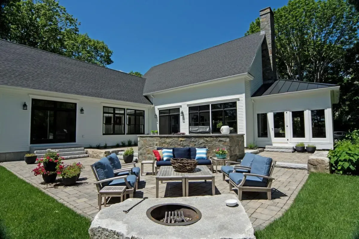 White Cape cottage with a fire pit in the front yard