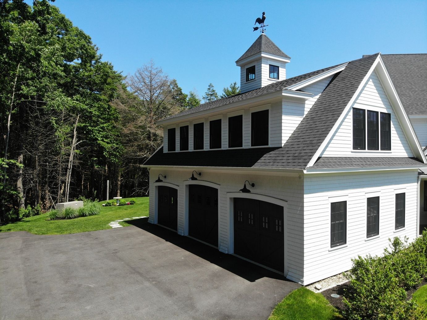 White garage with black doors and a rooftop weather vane