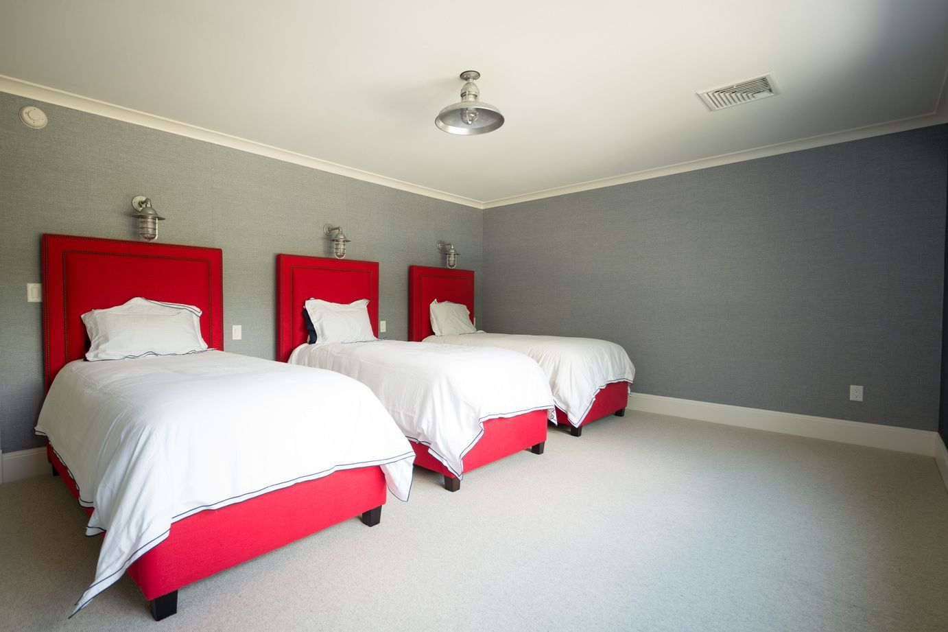 Bedroom with three beds and a ceiling-mounted projector