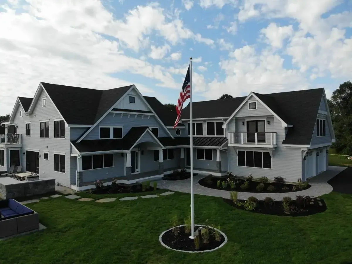 Renovated white Cape Elizabeth home with a flagpole at the front