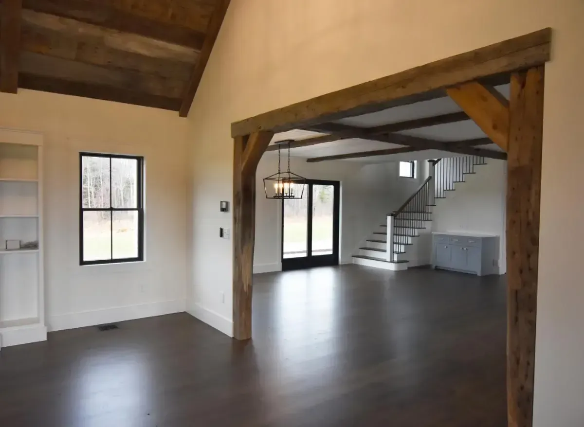 Unfurnished room with exposed wood beams and a staircase