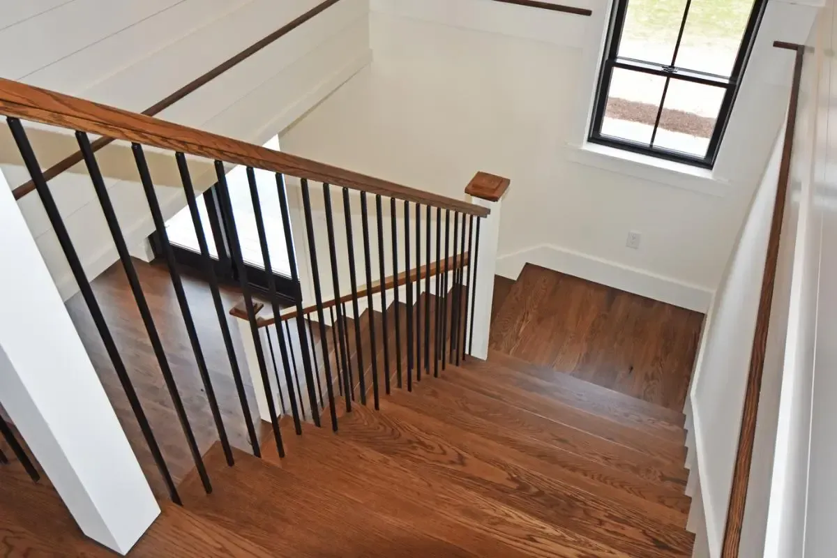 Wood staircase with a black railing beside a window