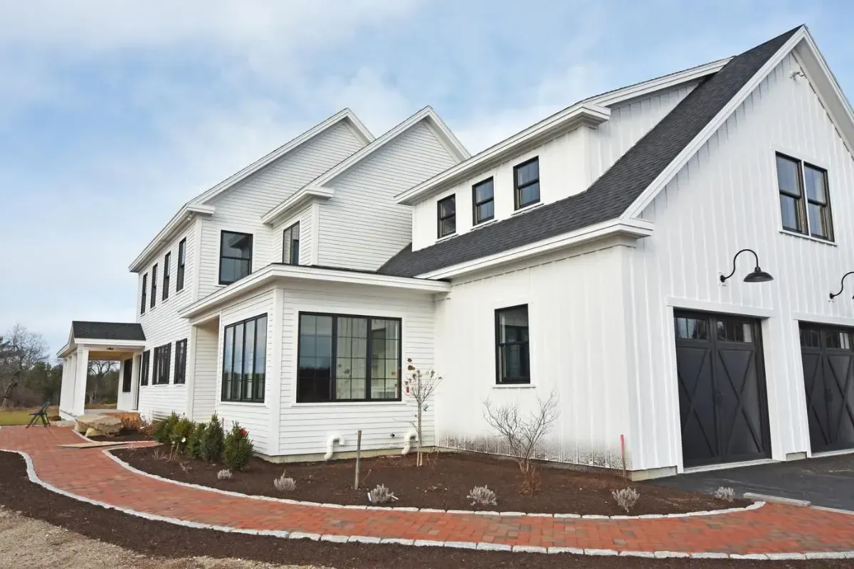 White Colonial with a black roof and brick front walk