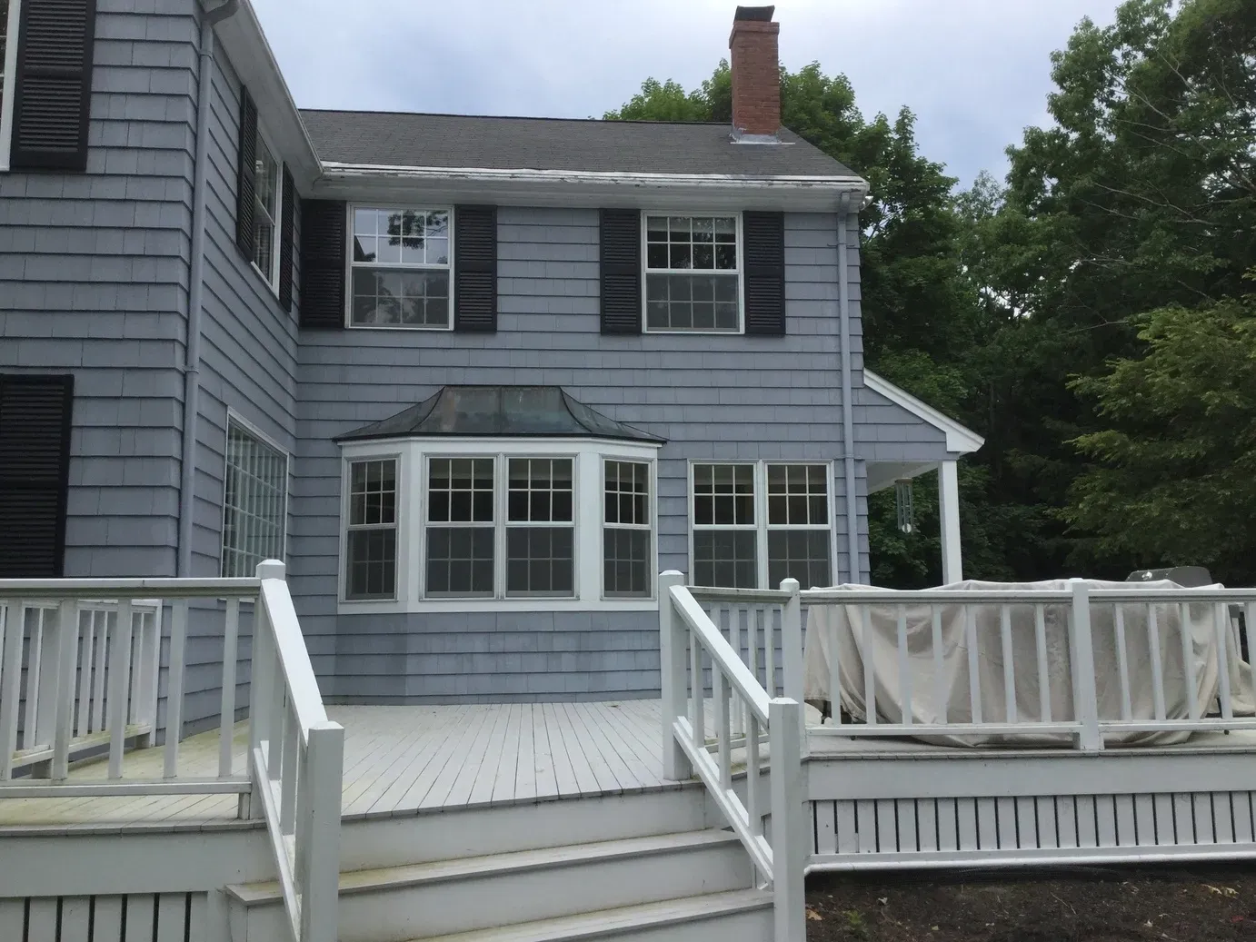 Blue Cumberland Foreside home with black shutters and a white deck after renovation