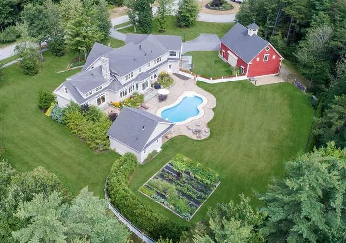 Aerial view of the estate home, pool, and red barn