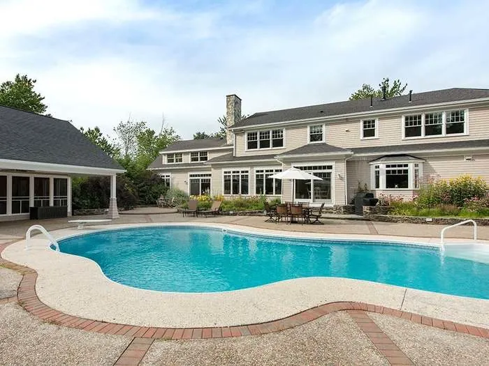 Pool and pool house surrounded by lawn and trees