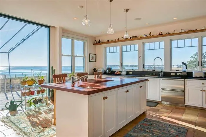Bright kitchen with a wood island and broad ocean views through the windows