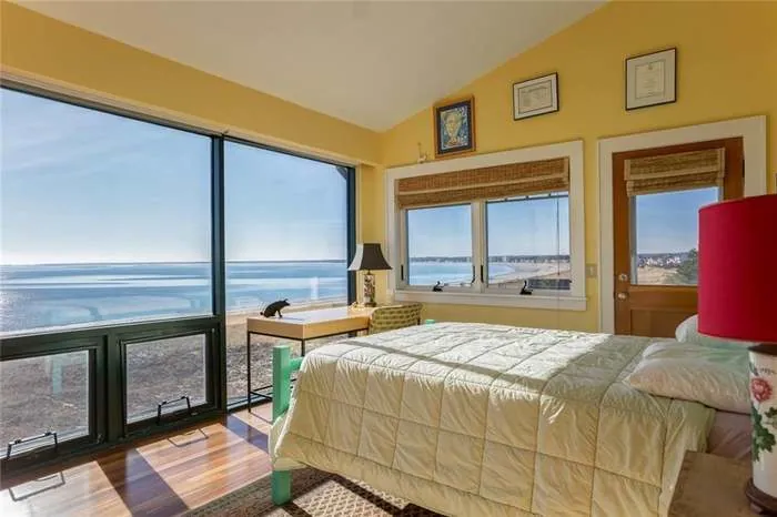 Coastal bedroom with broad windows and a water view