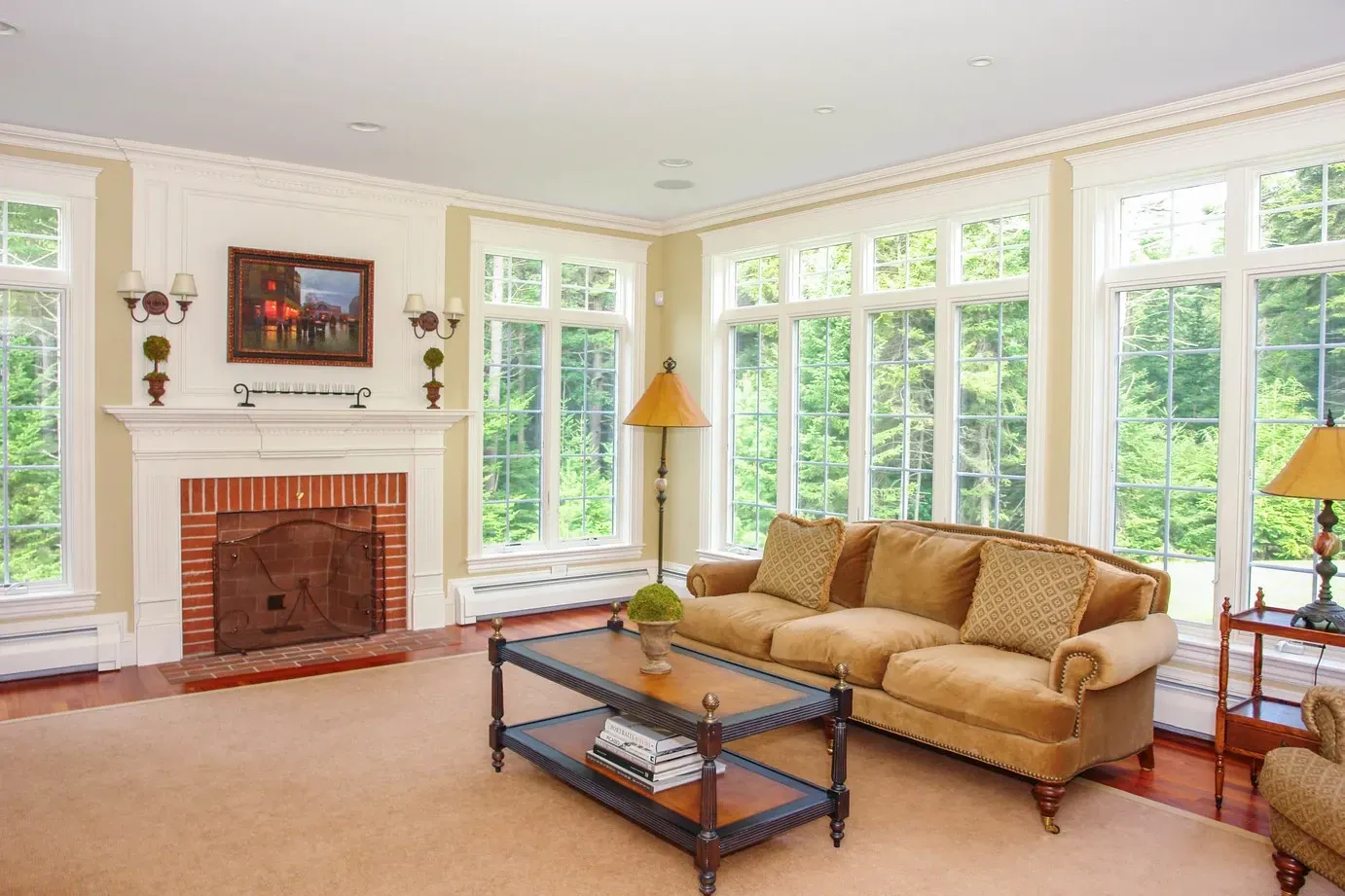 Living room with a fireplace, coffee table, and broad windows