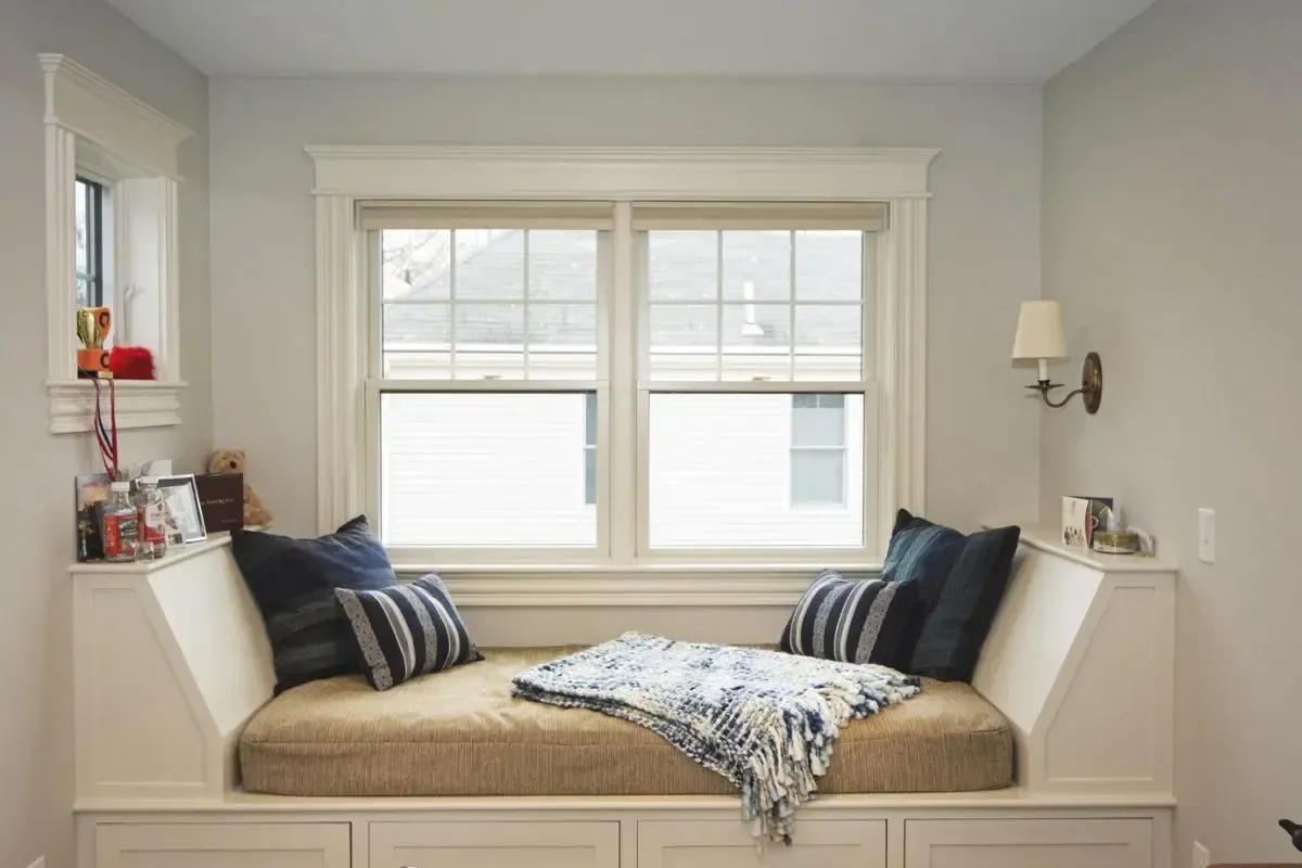 Window seat with cushions beside the bed