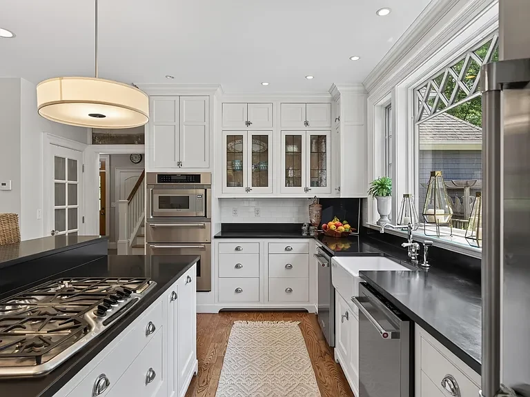 White kitchen with custom cabinetry, a dark island, and a broad work surface
