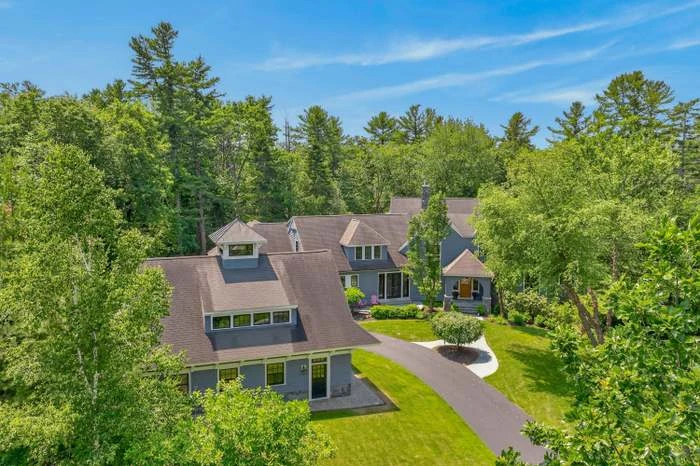 Aerial view of the Tiger Lily Lane home in Cape Elizabeth, set among mature trees with a curved driveway and landscaped grounds