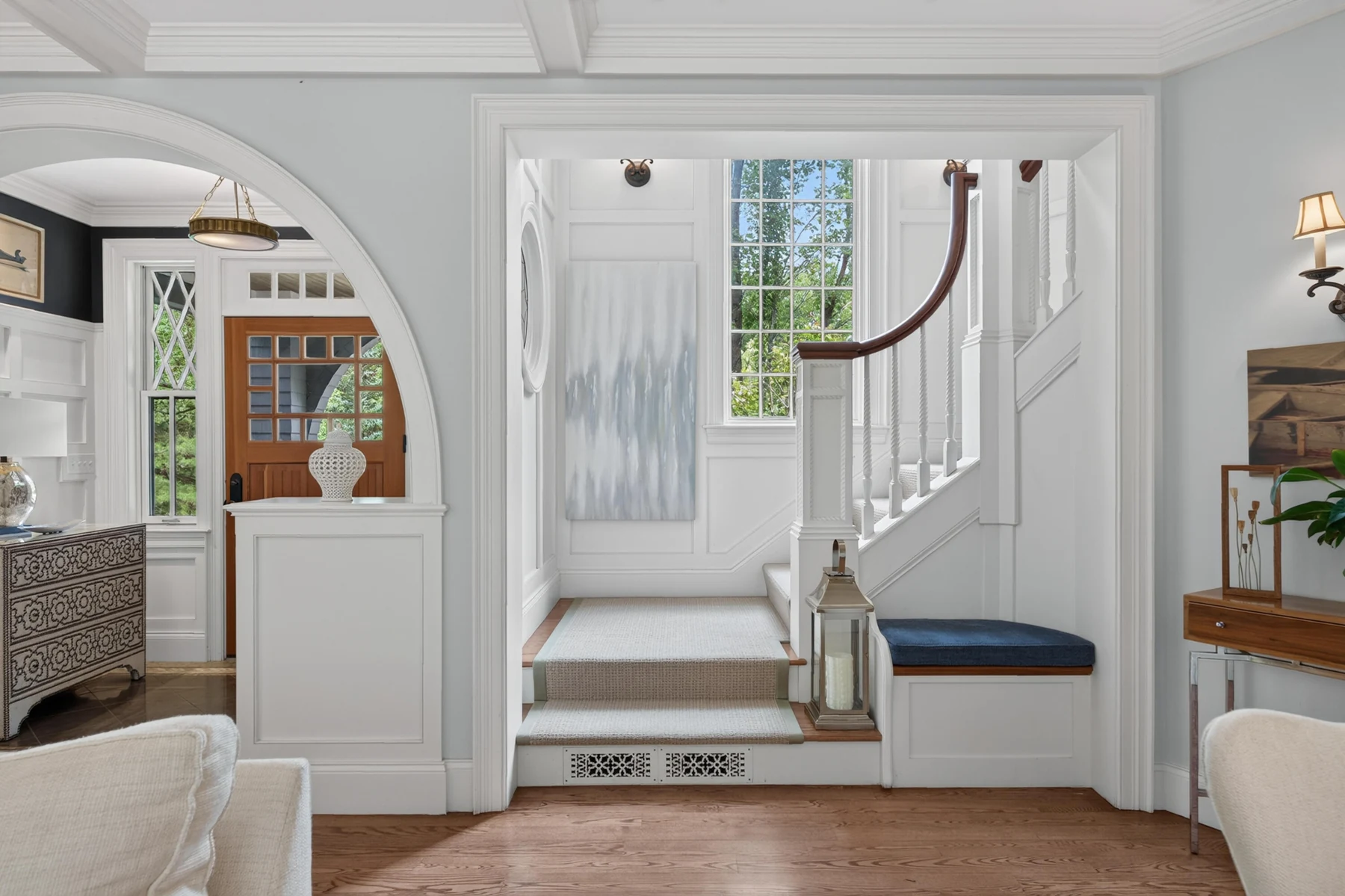 Curved staircase and fitted bench framed by an arched living-room opening
