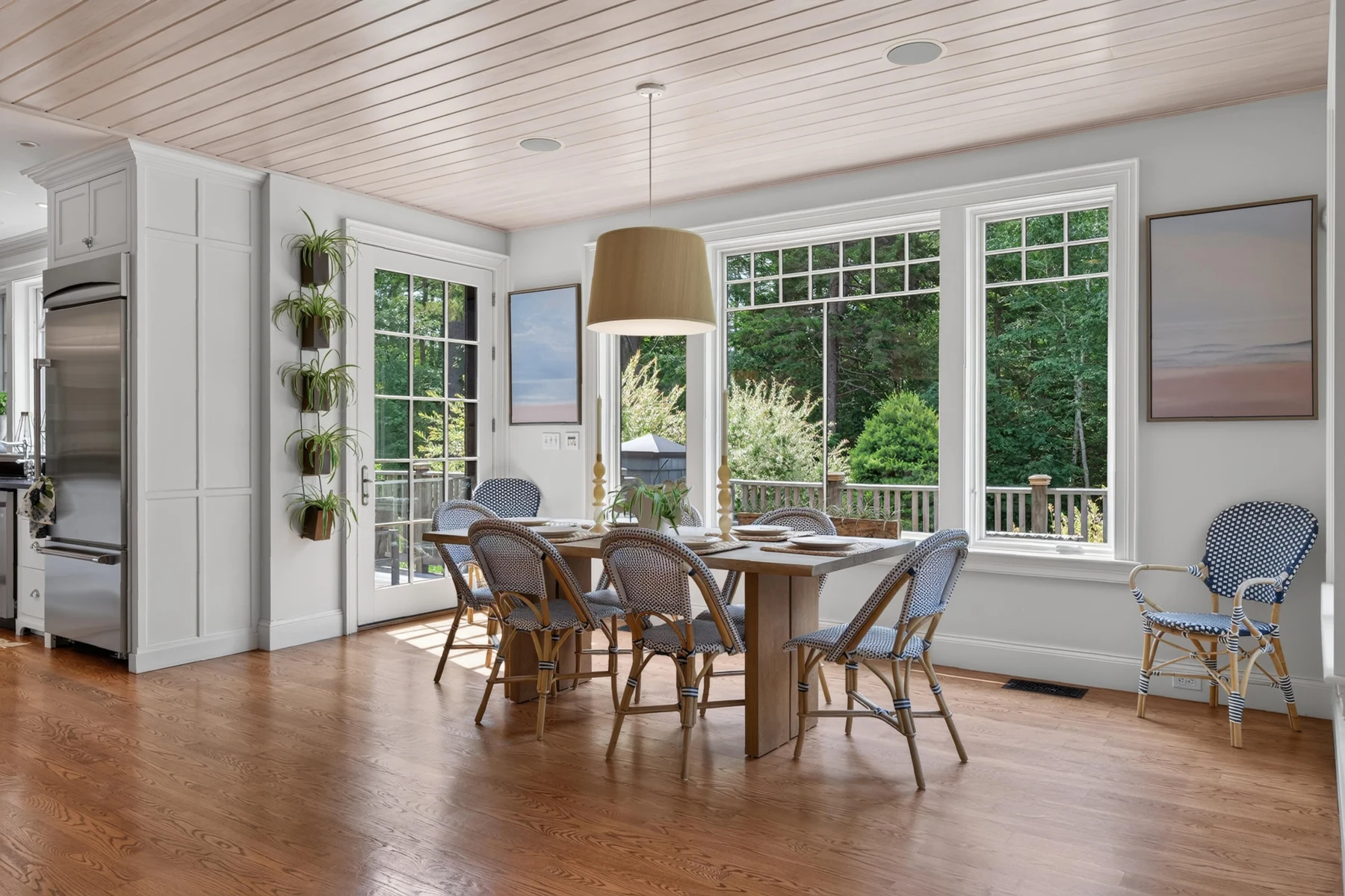 Window-lined breakfast room with a round dining table and wood ceiling
