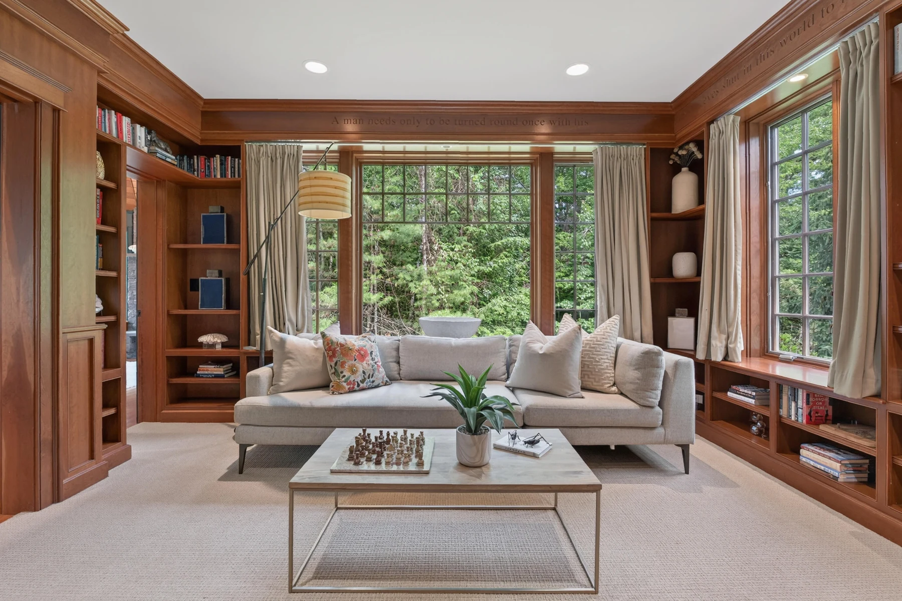 Wood-paneled library with fitted bookcases and broad windows