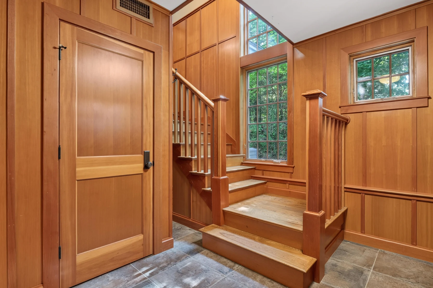 Wood staircase and paneled entry inside the carriage house