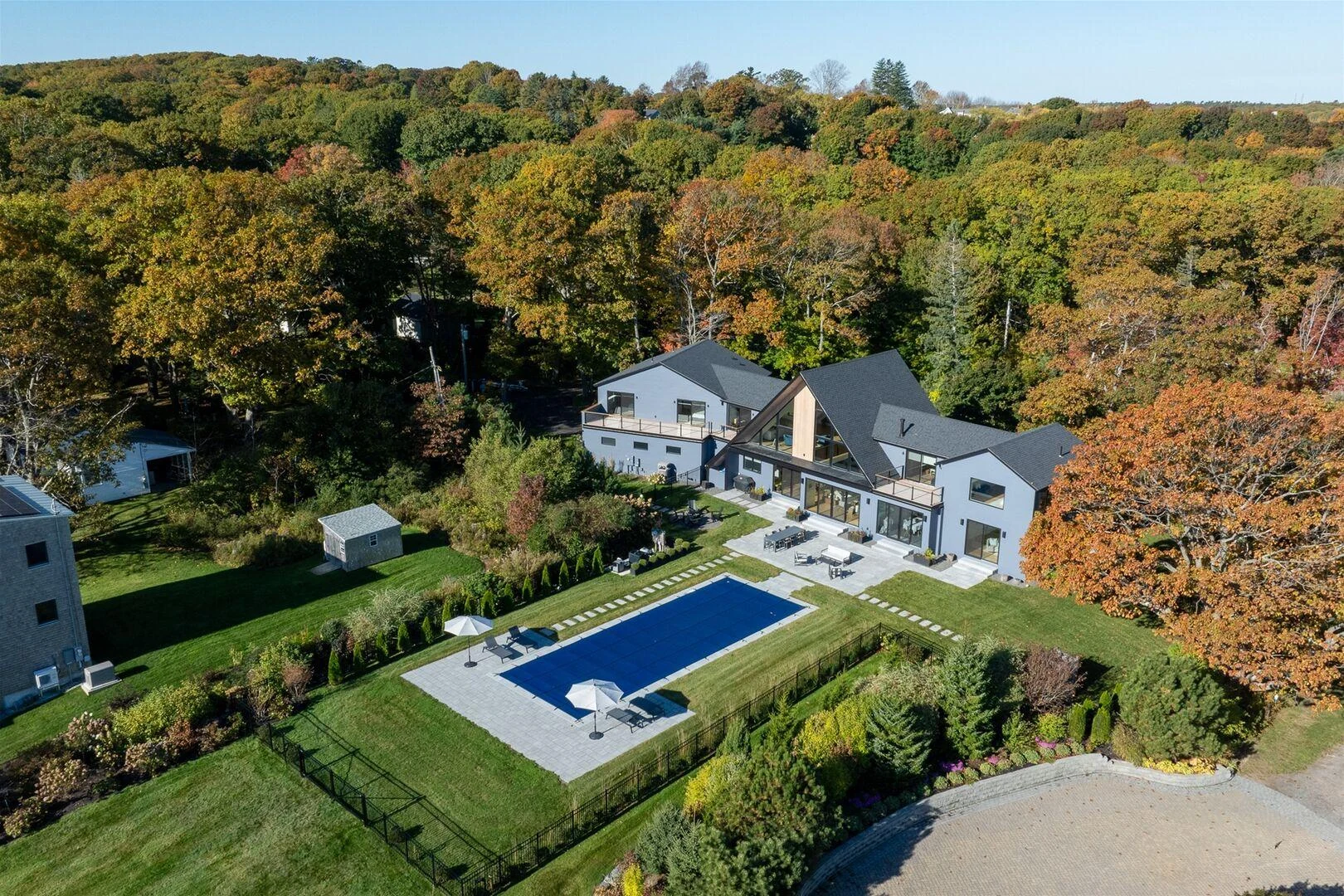 Rear aerial view of the coastal home, pool terrace, and surrounding trees