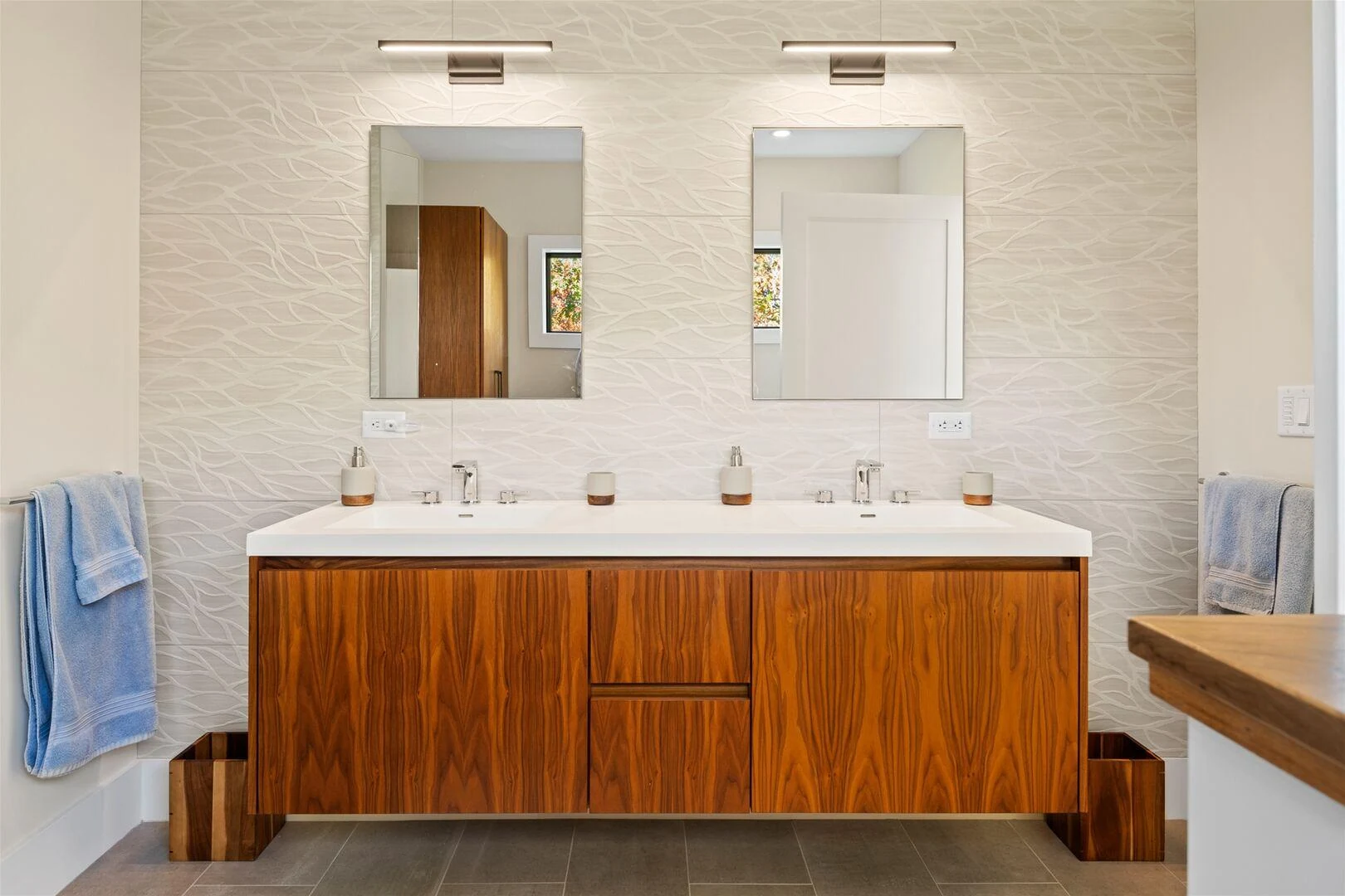 Wood double vanity with twin mirrors and a textured white wall