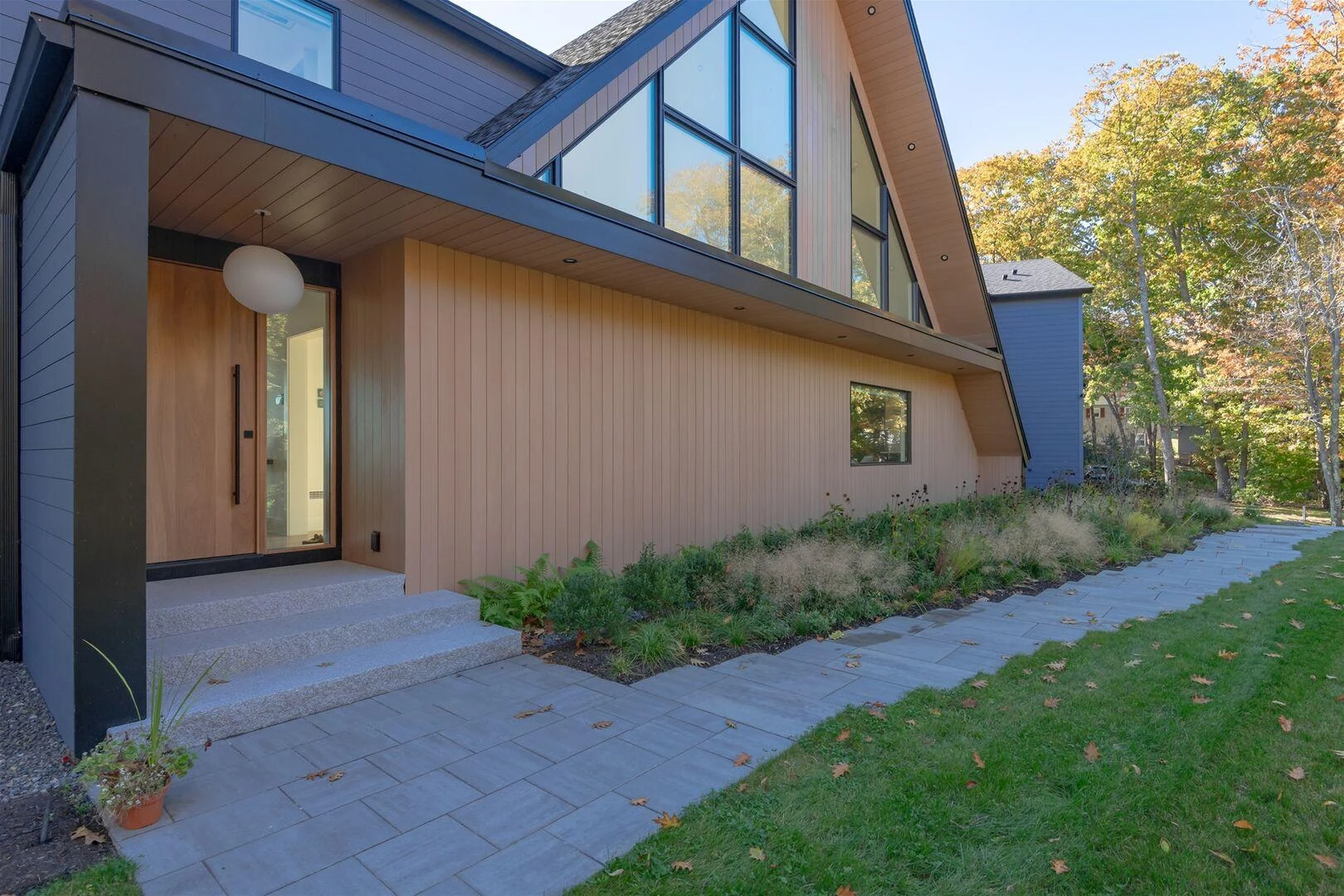 Wood-clad entrance beneath tall gable windows at the Trundy Point home