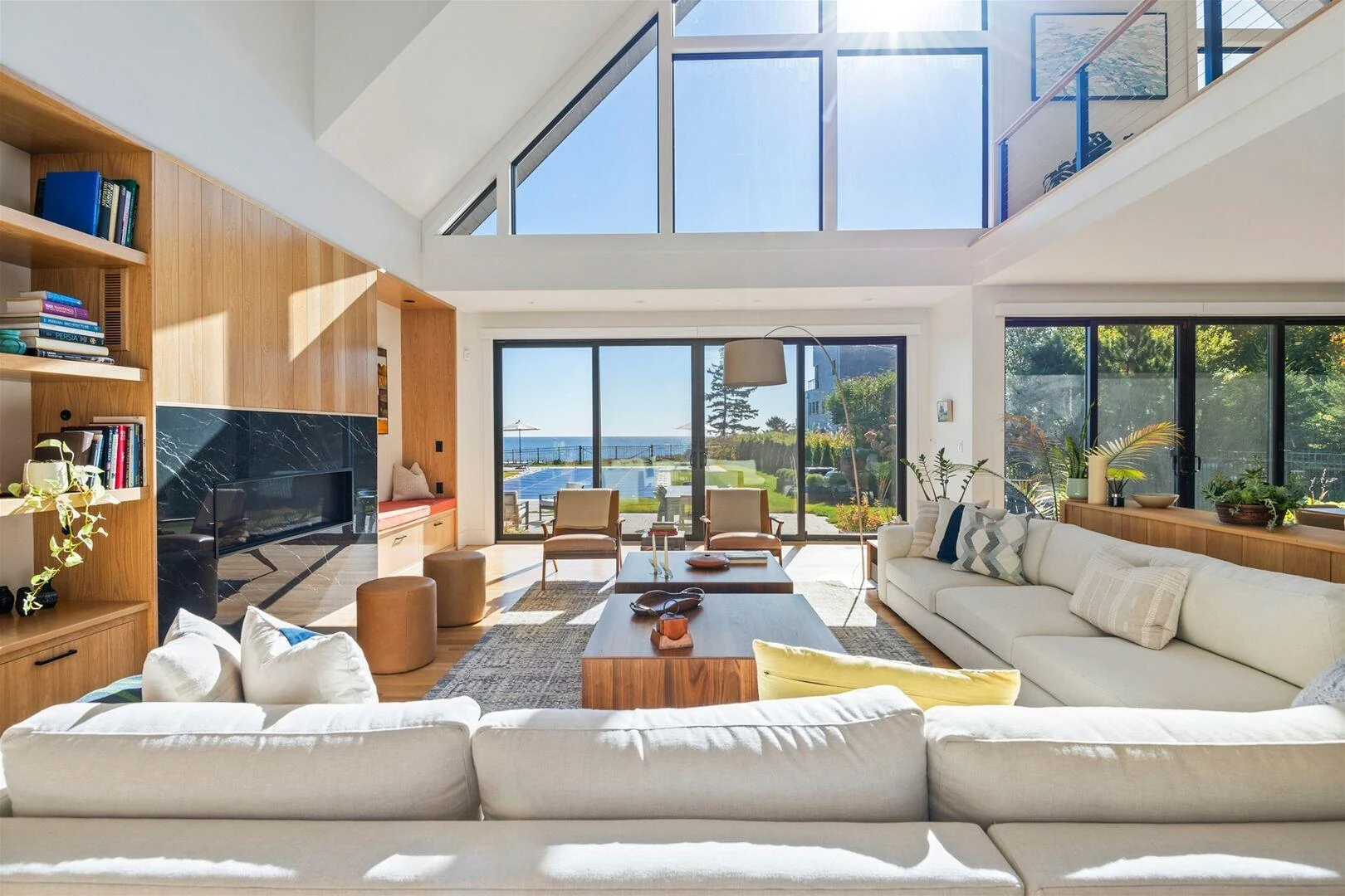 Double-height living room with wood cabinetry, a fireplace, and ocean views at Trundy Point