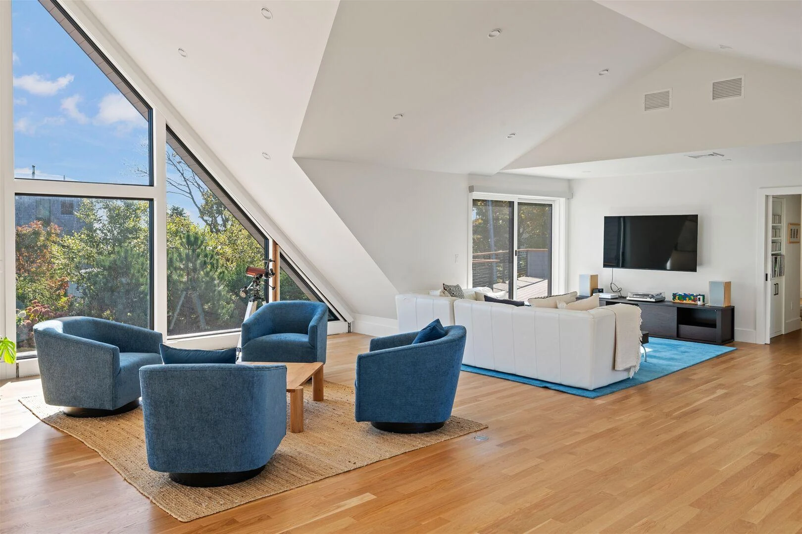 Upstairs lounge with blue chairs, a white sofa, and a television