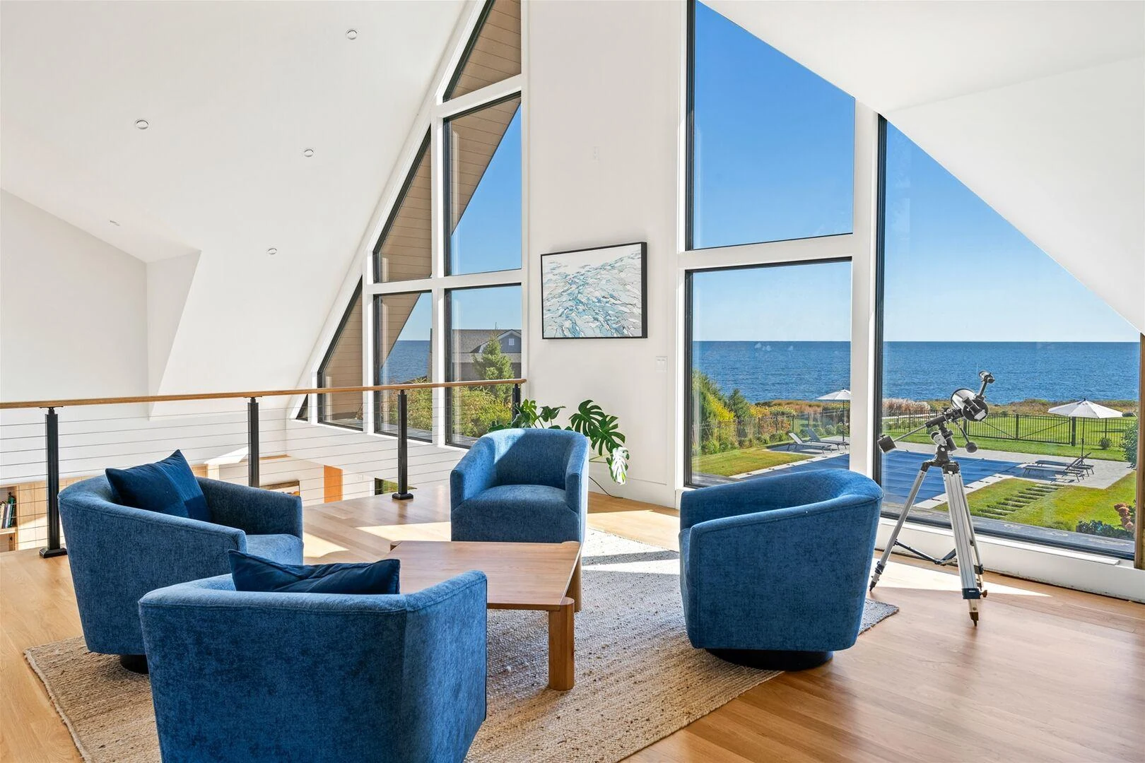 Upstairs sitting room with blue chairs and a telescope facing the ocean