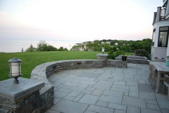 Stone terrace and lawn at the Shore Road residence, with the coast beyond
