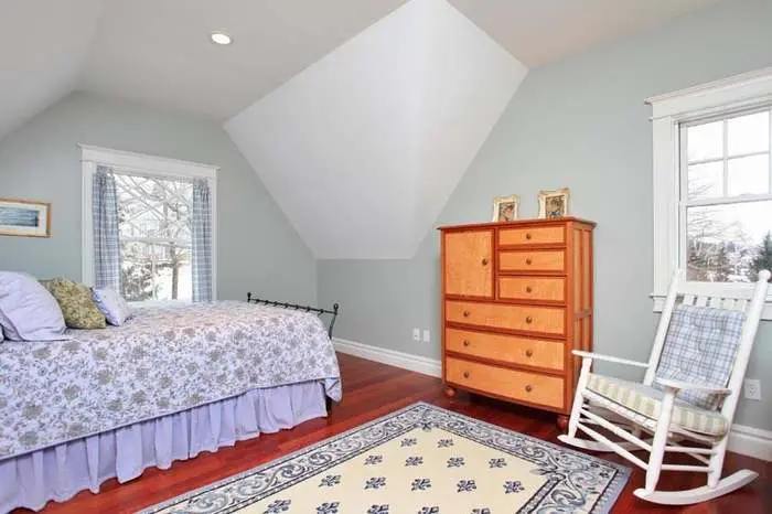Bedroom with a pitched ceiling, wood dresser, and white rocking chair
